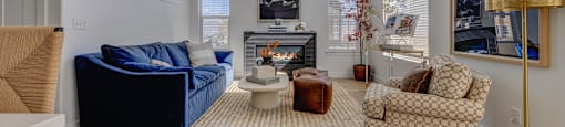 A living room with a blue couch, a patterned armchair, and a coffee table.