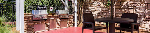 a patio with a barbecue grill and a table with two chairs