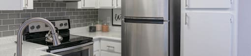 A kitchen with white cabinets and a stainless steel refrigerator at Westmount at Urban Trails, Mesa, AZ 85202