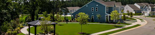a street with green lawns and blue houses at Ashford Townes Apartments, Fuquay-Varina, 27526