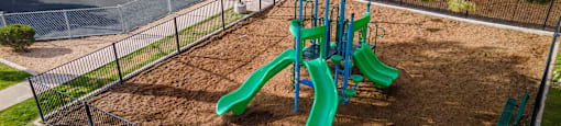 a playground with a blue umbrella and green playground equipment