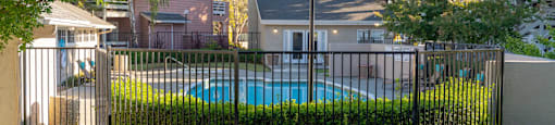 a swimming pool behind a wrought iron fence in a backyard