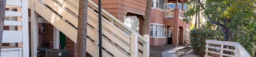 a pathway in front of a building with stairs and trees