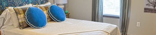 a bedroom with a bed with blue pillows on it