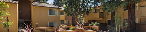 a courtyard with benches and trees in front of an apartment building
