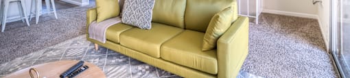 a living room with a yellow couch and a kitchen with a bar and a table