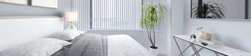 a white bedroom with a bed and a potted plant