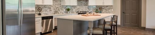 a large kitchen with a center island and stainless steel refrigerator