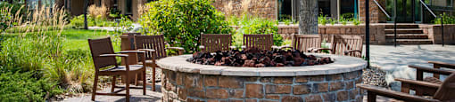 a patio with chairs and a fire pit in front of a house