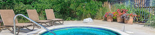 a hot tub in the backyard of a house with two chairs