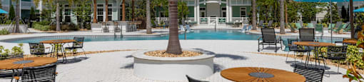 a swimming pool with tables and chairs and a house in the background