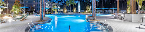 a swimming pool at night with palm trees