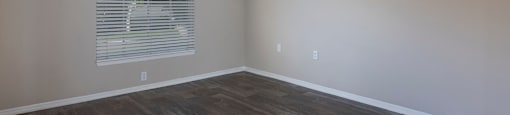 an empty living room with a ceiling fan and a window