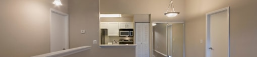 a renovated living room and kitchen with wood flooring and white walls