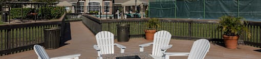 a patio with white chairs and a fire pit