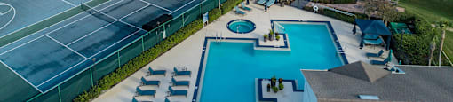 a aerial view of a pool and tennis court and a lake