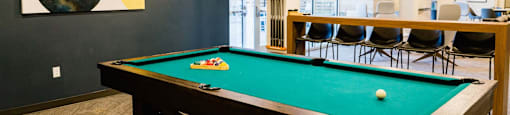 a pool table in a room with a bar and a painting