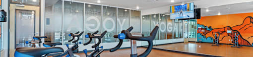 a gym with cardio bikes and a wall of windows