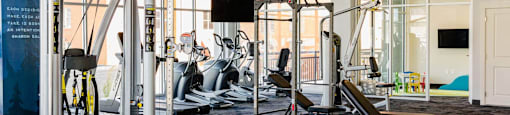 a gym with weights and cardio equipment in a room with glass walls