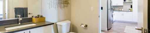 a bathroom with a toilet and a sink and a refrigerator