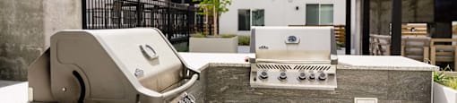 a grill and smoker on the patio of an apartment building