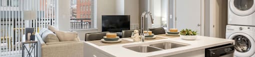 a kitchen and living room with a washing machine and a washer and dryer