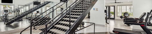 a spiral staircase in a gym with treadmills and chairs