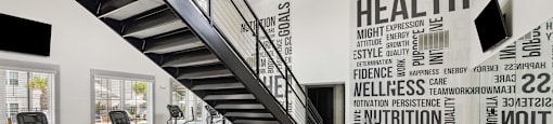 a gym with stairs and weights and a wall with words on it