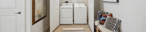 a laundry room with a washer and dryer and a chair