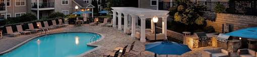 an outdoor pool with tables and umbrellas at dusk