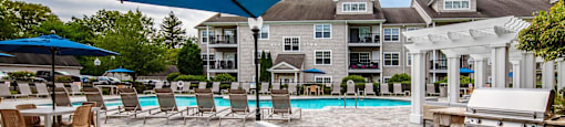 a large pool with chairs and umbrellas and a building in the background