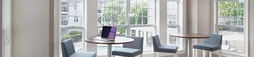 a living room with tables and chairs and a laptop