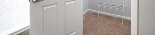 a walk in closet with a white door and a closet with white racks