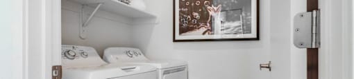 a small laundry room with a washer and dryer and a painting on the
