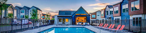 a swimming pool with chairs around it at dusk