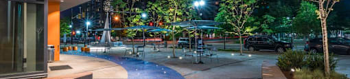 A park at night with benches and trees.