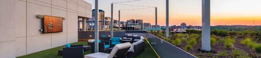 A rooftop patio with a string of lights and a view of the city skyline at dusk.