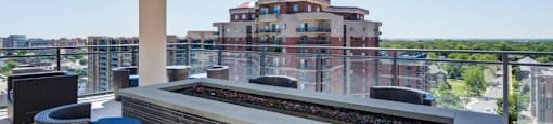 A barbecue grill is on a patio with a view of a building in the background.