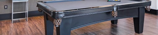 A pool table in a room with a light brown floor.