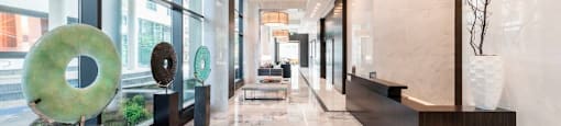 A hallway with marble floors and a large window on the left.