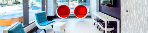 A modern waiting room with blue and red chairs and a television.