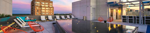 A rooftop patio with a table and chairs overlooking a pool.