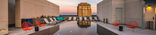 A modern outdoor seating area with orange chairs and a reflective pool.