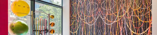 A room with a red carpet and a wall with a colorful string art.
