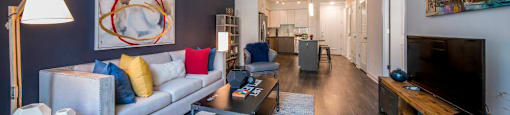 A living room with a white couch, a coffee table, and a television.