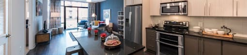 A modern kitchen with a black countertop and stainless steel appliances.