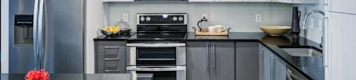 A modern kitchen with a black countertop and stainless steel appliances.
