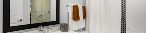 A white bathroom with a black framed mirror.