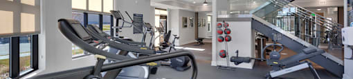 A gym with a treadmill and a staircase.