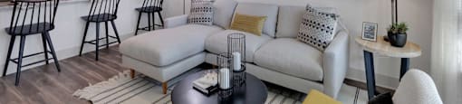 A modern living room with a white sofa, a black coffee table, and a large abstract painting on the wall.
